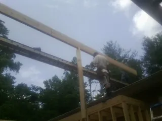 Carpenter setting a ridge beam over a new addition frame — Ice Dam Removal by Roofing Brothers in Saint Rose