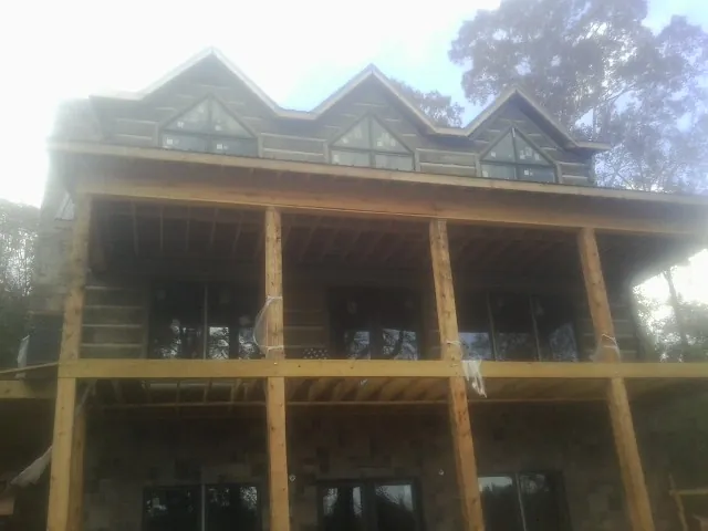 Dormers and porch framing on a large log home under construction — Roof Coating work by our crew in Saint Rose