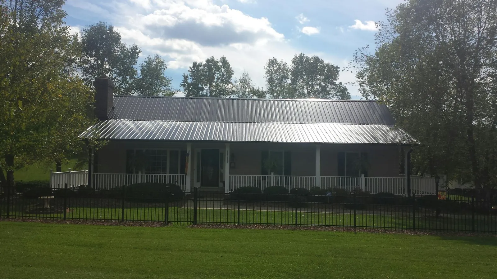 Gray metal roof on a brick ranch with a full width front porch — Gutter Guard Installation work by our crew in Saint Rose