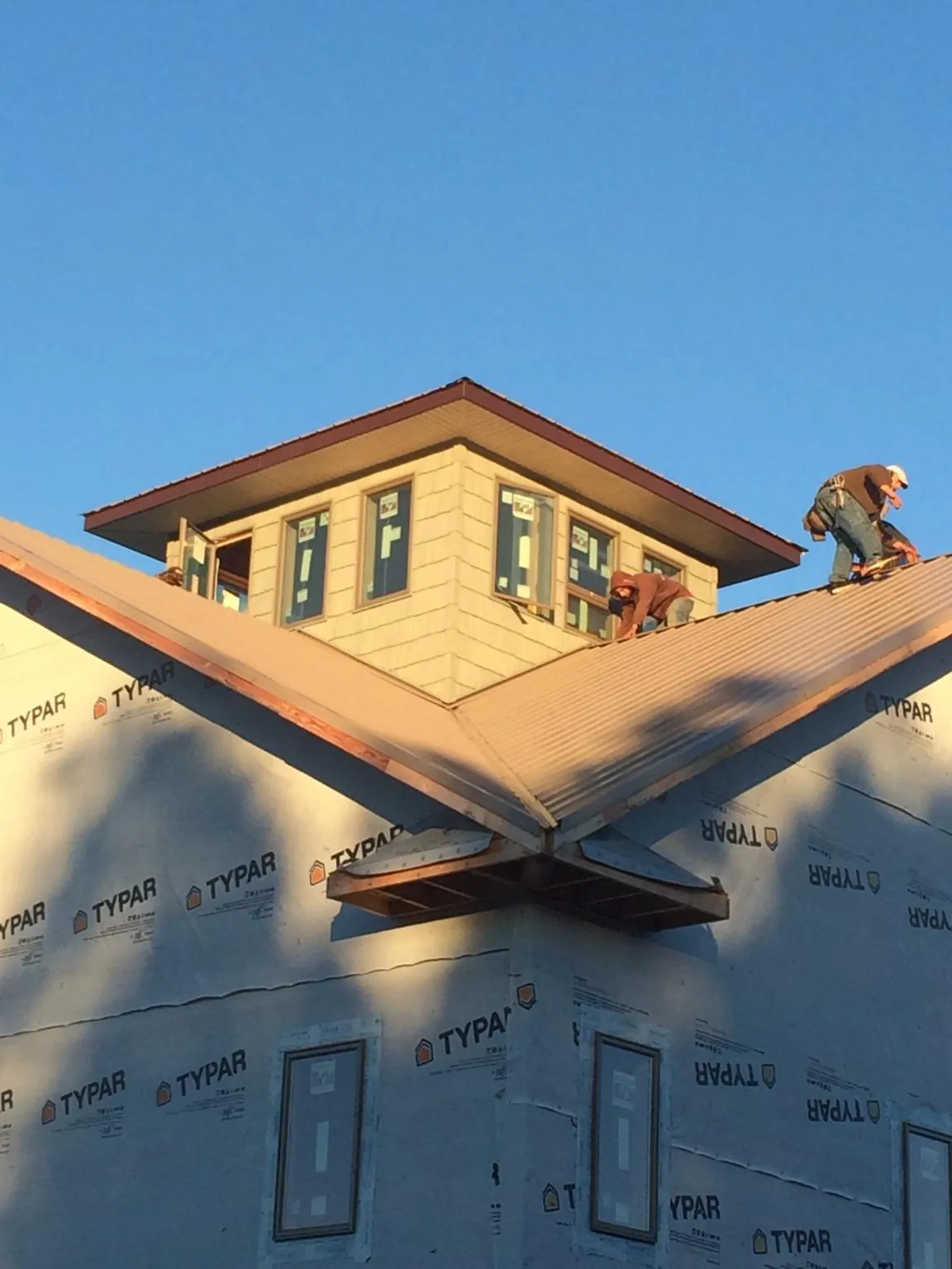 Roofers working around a rooftop cupola on a new metal roof at sunset — Roof Waterproofing in Saint Rose by Roofing Brothers
